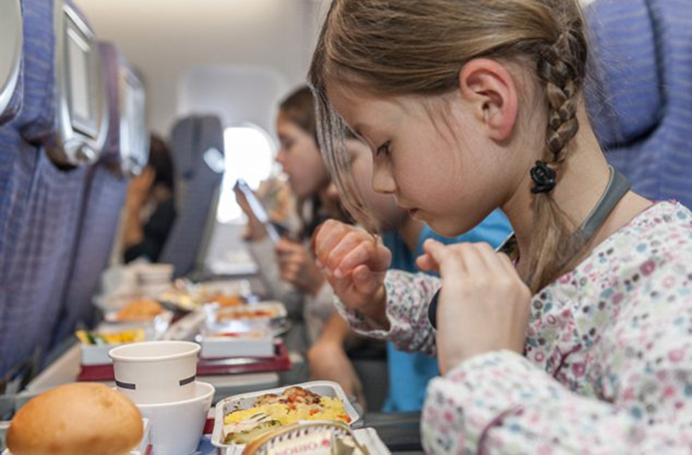 Girl about to eat airline meal --- Image by © PhotoAlto/Corbis
